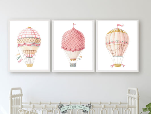 set of 3 watercolour pink Hot Air Balloon Prints. Whether adorning a nursery or adding a pop of colour to a dorm room, these vibrant prints are as playful as they are versatile, making them an ideal choice for both personal decor and thoughtful gifts for any occasion.