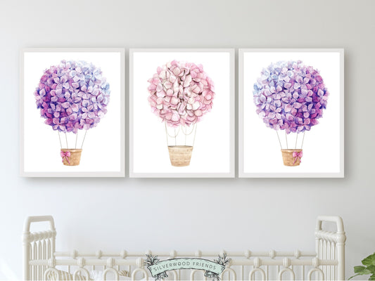 Set of 3 watercolour Hot Air Balloon Prints, featuring delightful pink and purple wildflower adorned balloons. A charming addition to your nursery decor and also makes an adorable baby shower gift, these prints infuse sweetness and elegance into any space.