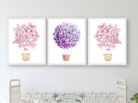 Set of 3 Watercolour Hot Air Balloon Prints, perfect for adding a whimsical touch to trendy dorm rooms or teen girl's bedrooms with their delightful pink and purple wildflower adorned balloons.