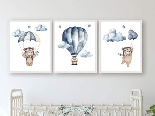 This delightful Set of 3 Teddy Bear Nursery Print Set of 3 showcases adorable watercolour teddy bears embarking on adventures amidst a dreamy star-studded sky in a hot air balloon, parachute and holding balloons.